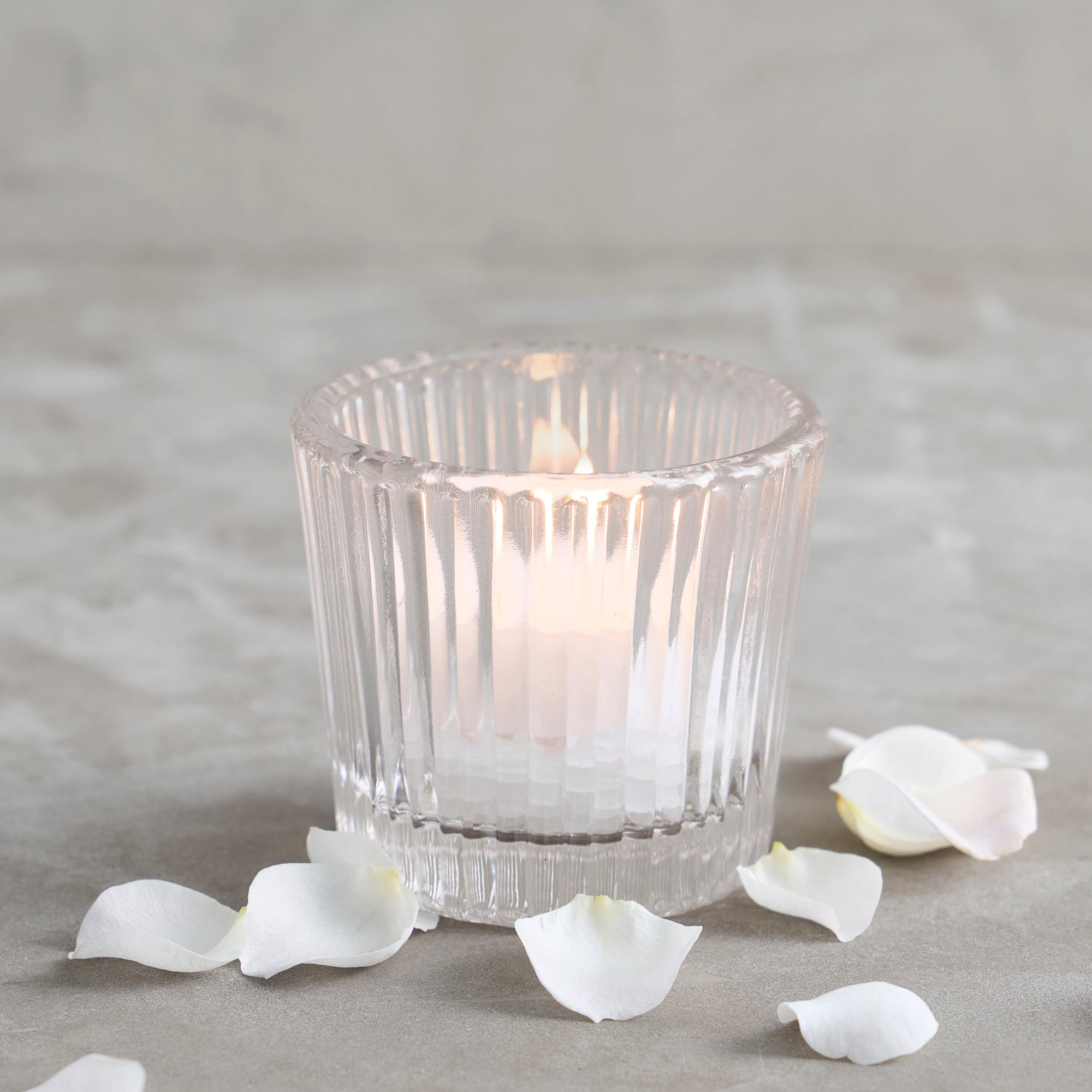 Glass votive candle holder with a lit candle inside - candleholder collection at Better World Bio