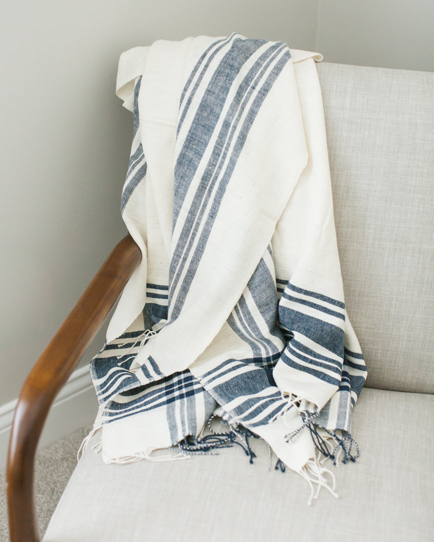 Blue striped cotton throw blanket folded over a chair