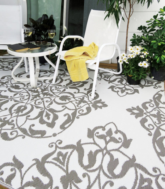 Beige and white outdoor rug with a chair and table on top - outdoor rugs and mats collection at Better World Bio