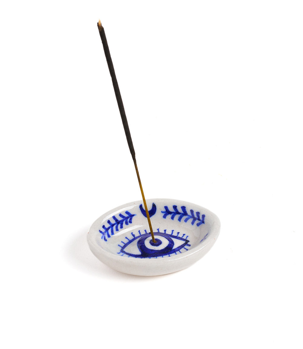A hand painted blue and white ceramic incense holder holding an incense stick