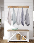 Set of striped towels hanging on a rack against a white wall with a wooden bench below