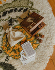A wooden game night box with brass inlay, containing playing cards and dice on a carpet.