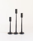A set of three black finish iron candlesticks in varying heights, displayed against a white background.