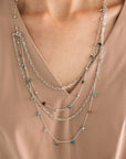 A person wearing a layered chain necklace with small beads