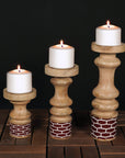 Three wooden candle holders with candles on a dark background
