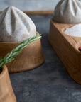 Wooden trays and reamers with salt, pepper, and a herb on a dark surface