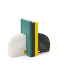A pair of marble bookends featuring one with a sun design and the other with a moon design, in black, white, and brass colors, with books positioned between them.