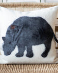 Decorative pillow with a rhinoceros design on a wicker chair.