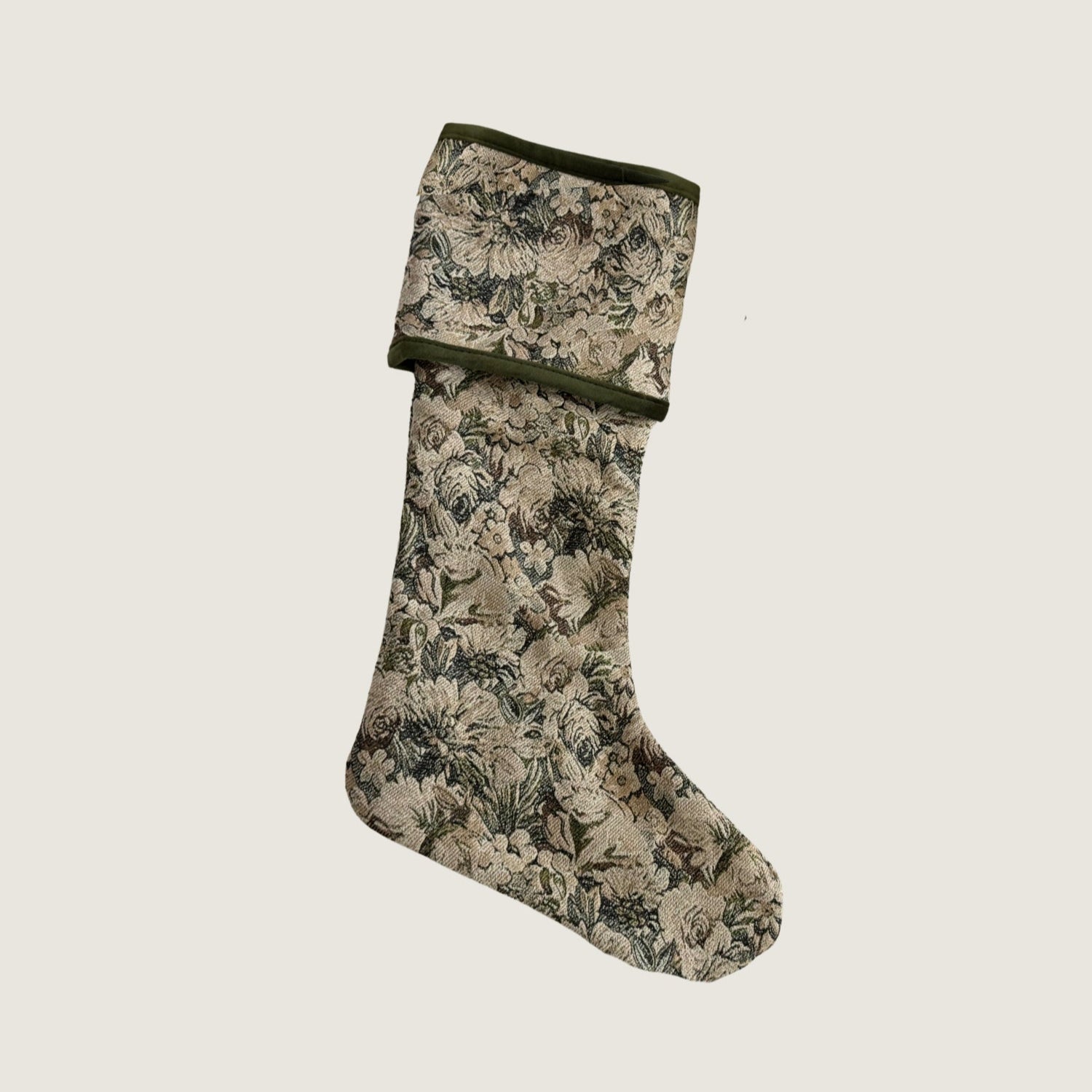 A reversible holiday stocking featuring a floral tapestry design in green, white, and light brown, with green velvet piping