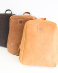Three leather book bags in brown, tan, and dark brown colors, displayed upright against a white background.