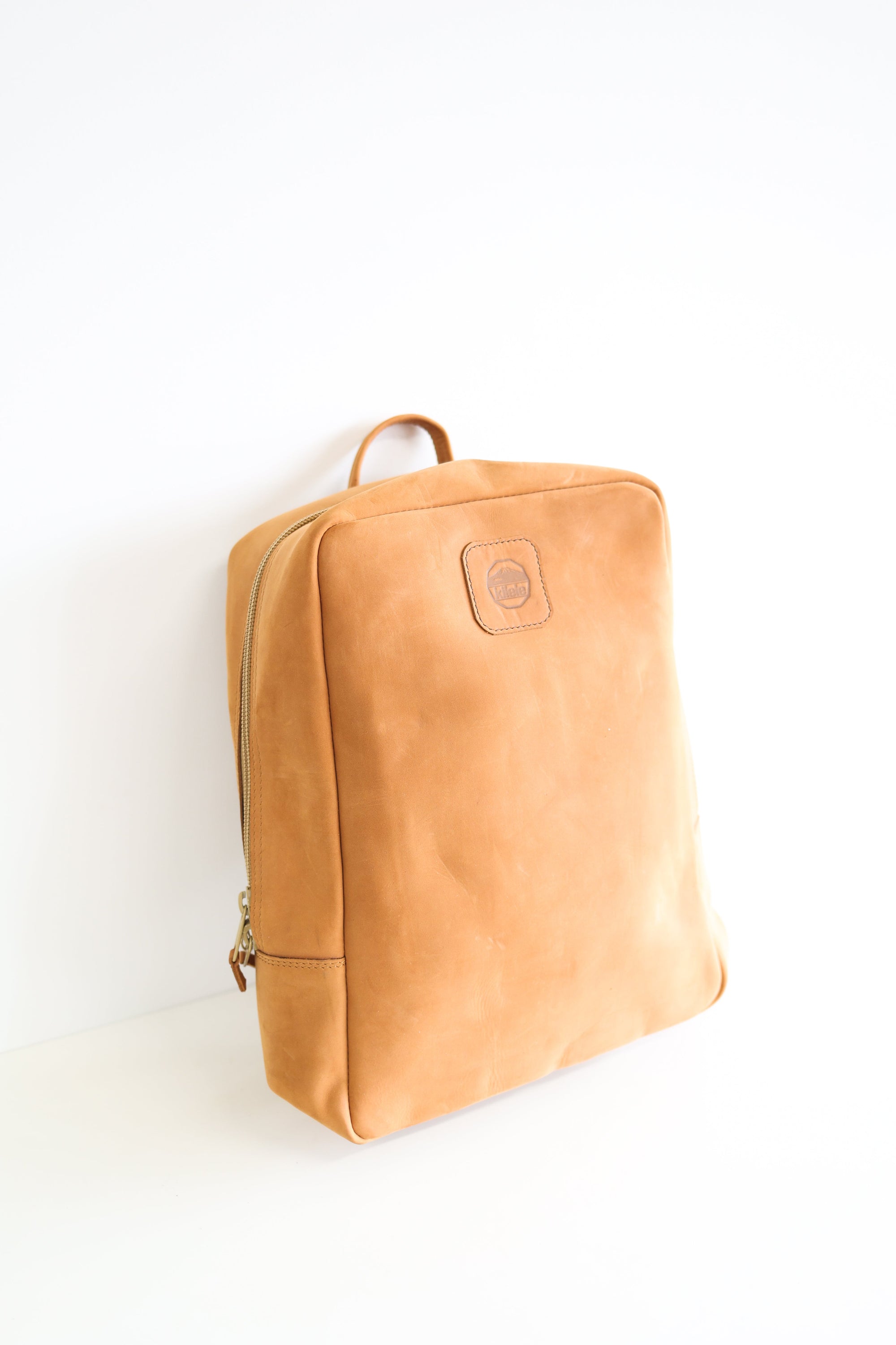 A leather book bag in tan, displayed upright against a white background.