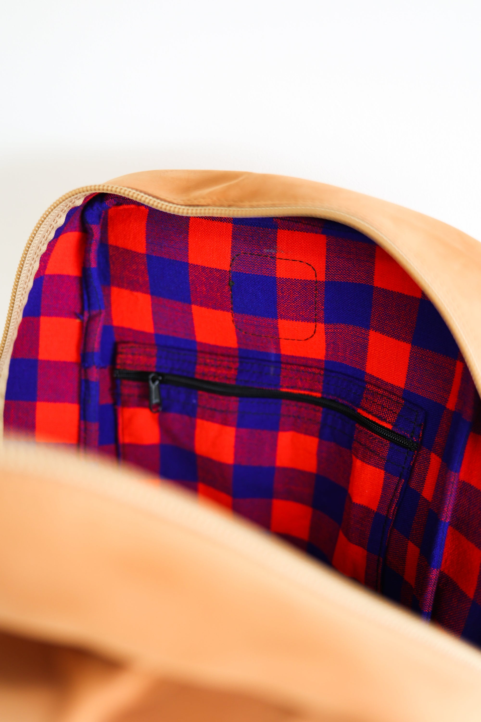 Up close view of the inside of a leather book bag in tan, displayed upright against a white background.