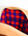 Up close view of the inside of a leather book bag in tan, displayed upright against a white background.