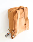 The back of a leather book bag in tan, displayed upright against a white background.