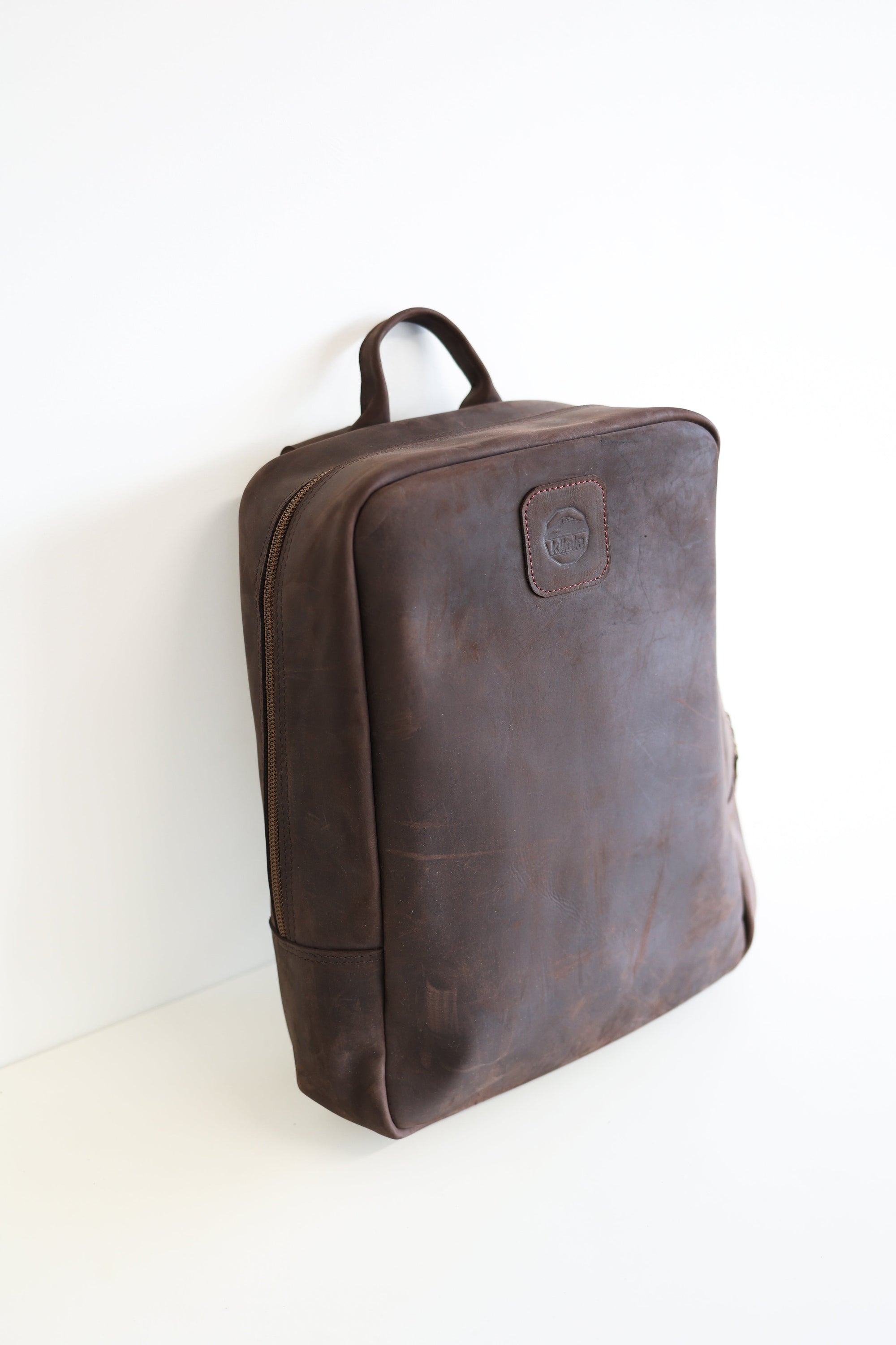 A leather book bag in brown, displayed upright against a white background.