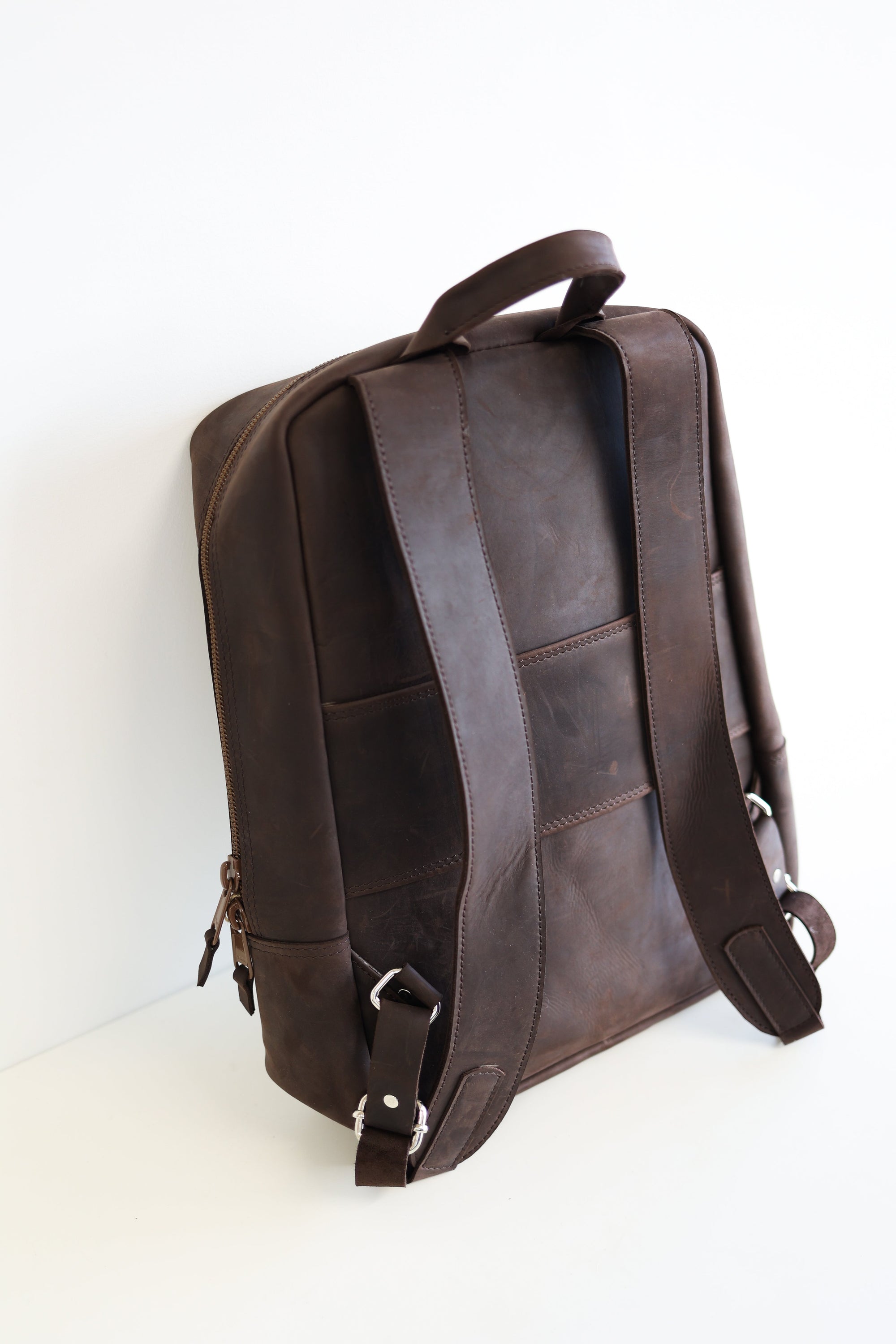 The back view of a leather book bag in brown, displayed upright against a white background.