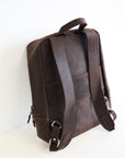 The back view of a leather book bag in brown, displayed upright against a white background.