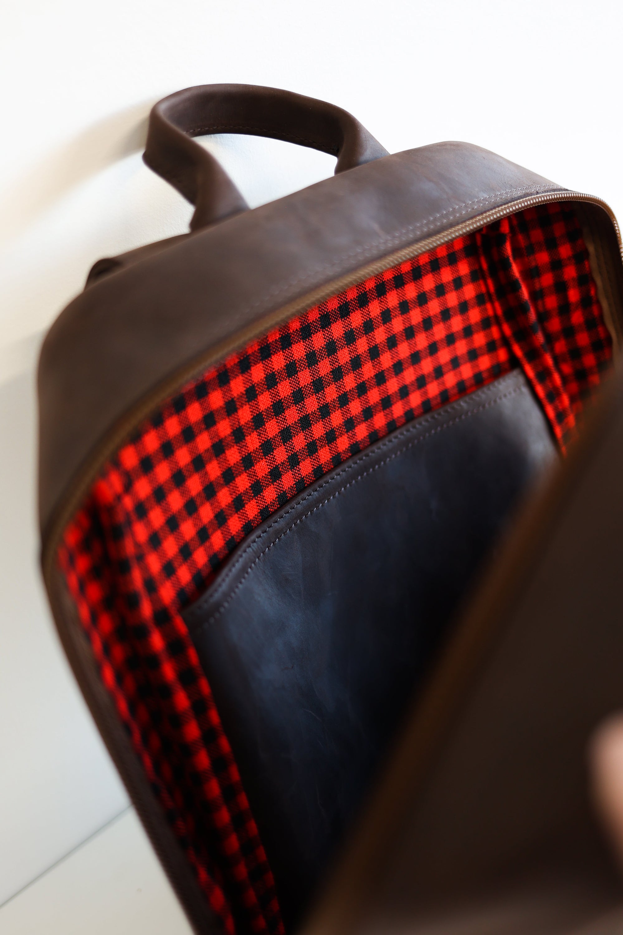 An unzipped inside view of a leather book bag in brown, displayed upright against a white background.