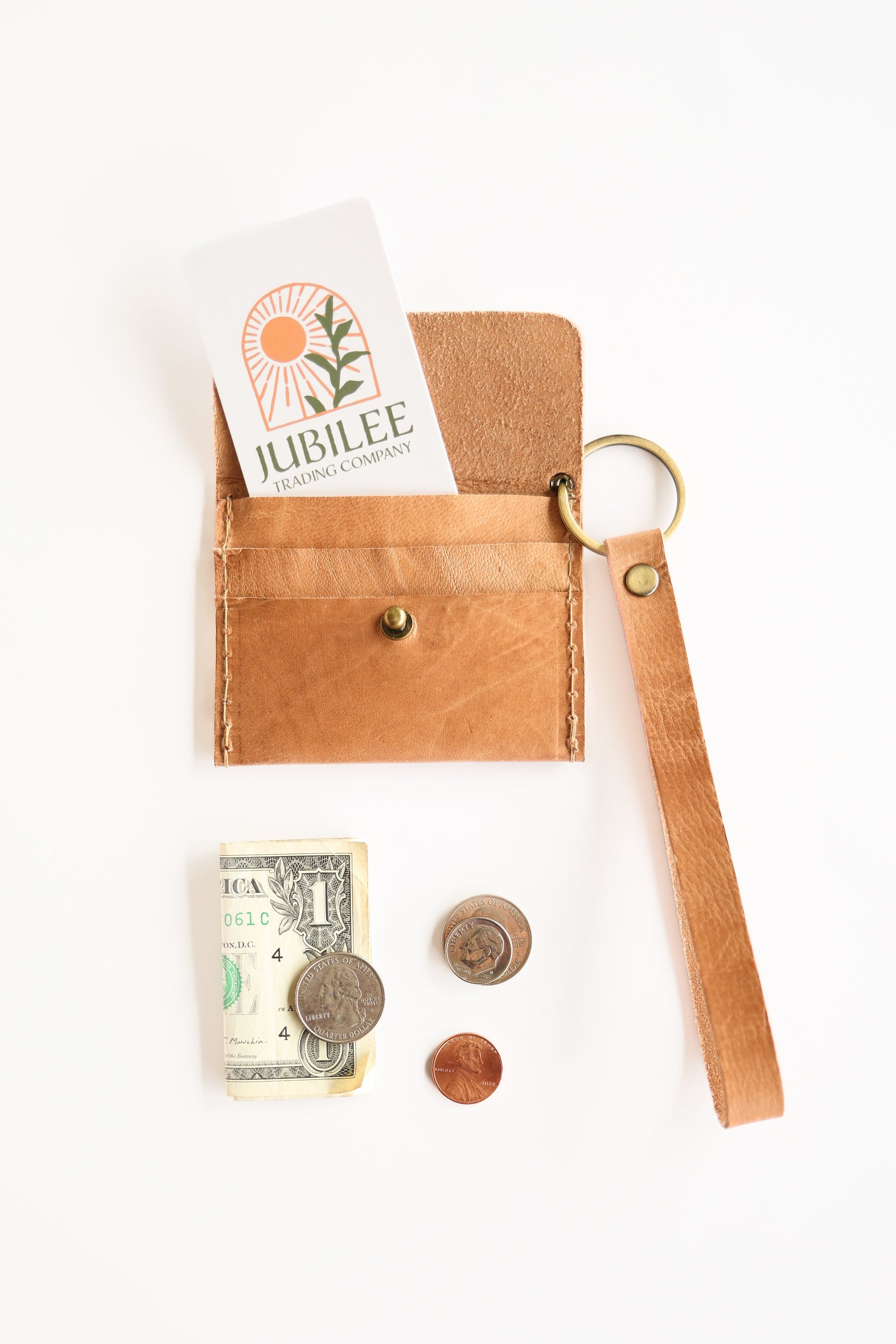 Brown leather wallet with keychain, money, and coins on a white background