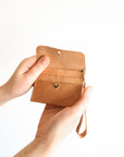 Brown leather wallet held by a hand on a white background