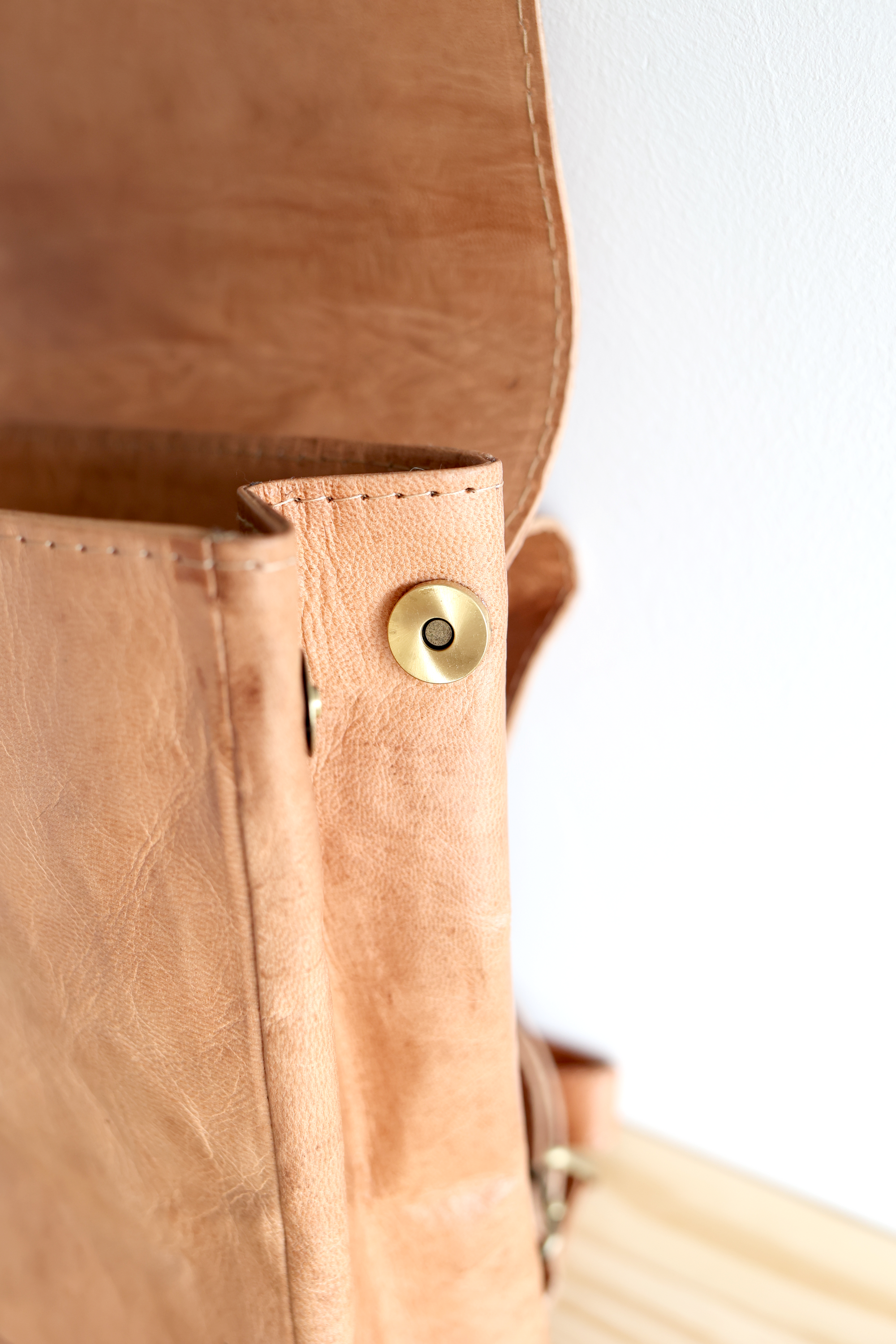 Close-up of a brown leather bag with a gold clasp on a white background