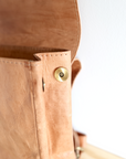 Close-up of a brown leather bag with a gold clasp on a white background