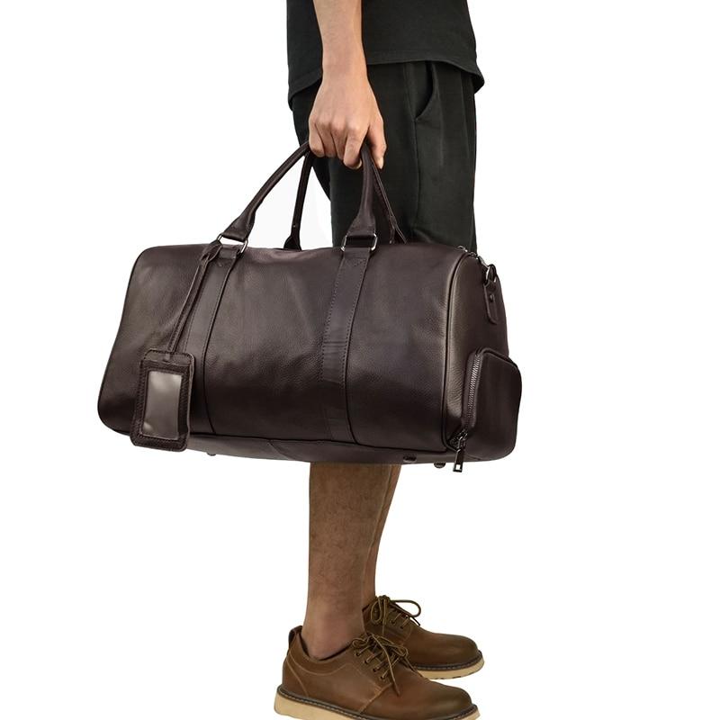 A person carrying a brown leather weekender bag with a leather handle and visible stitching details.