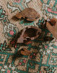 Wooden sea turtle puzzle box being put together by a hand on a carpet.