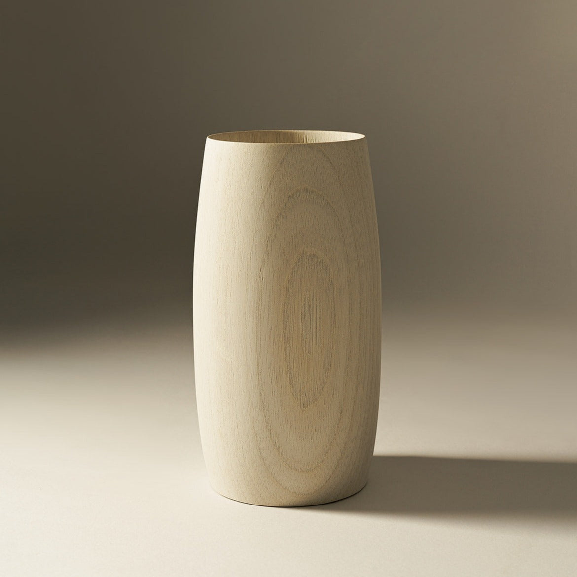 A beige, cylindrical wooden vase with a smooth finish, displayed against a neutral background.