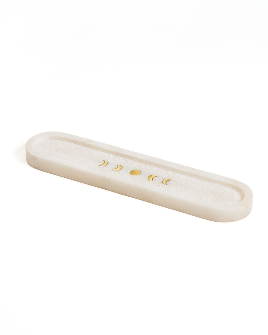 A white carved marble incense holder with brass moon phase design on the front, featuring two holes on each end for incense sticks.