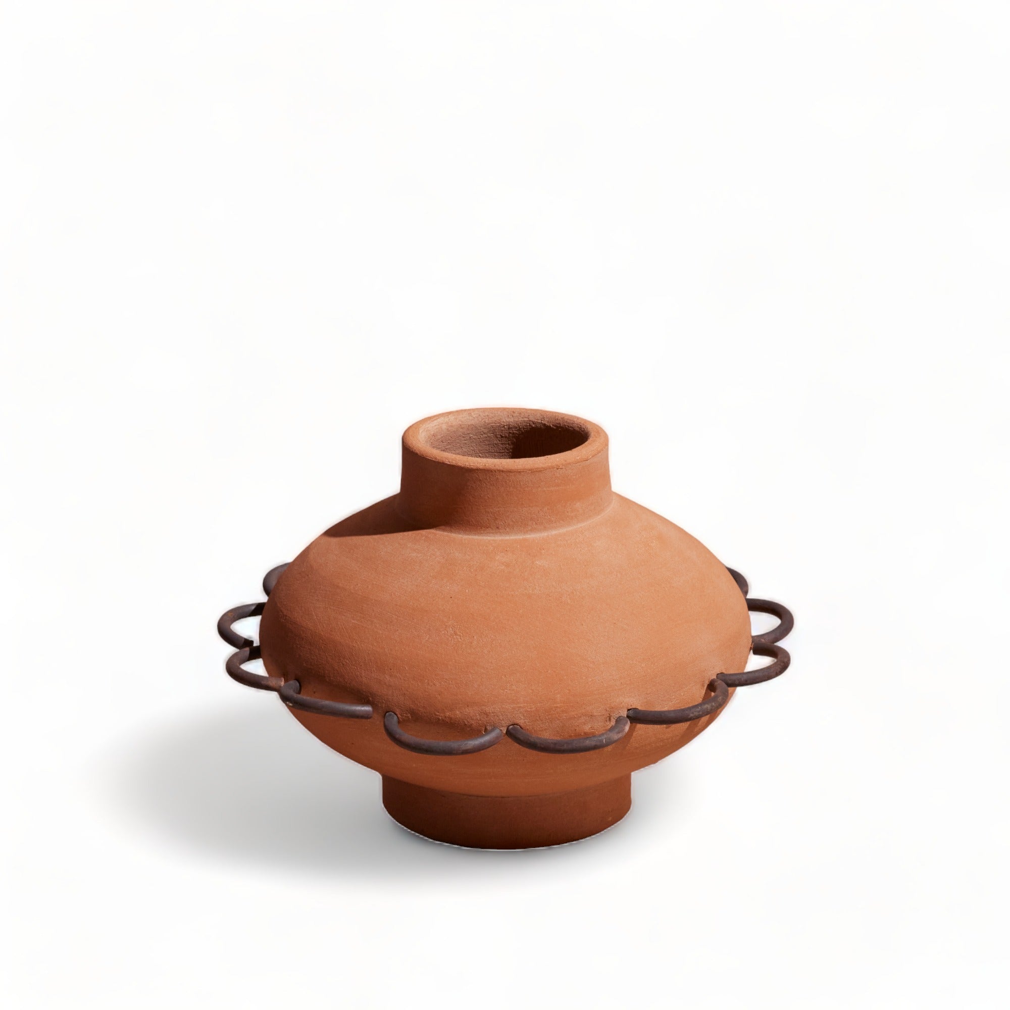 A brown terracotta scalloped vase with visible handcrafted texture and metal accents on the rim.