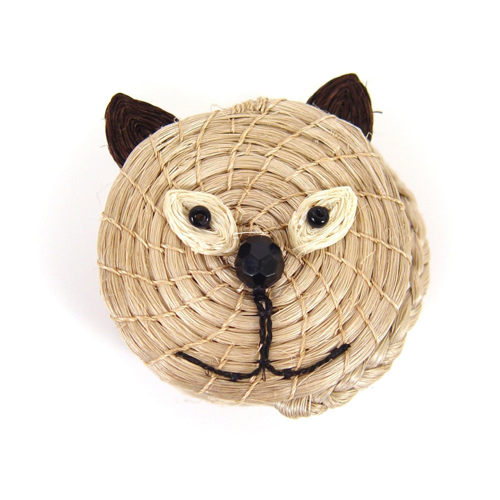 A handwoven beige basket with a face resembling a cat, including ears, eyes, and a nose, made from sisal