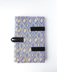 A closed jewelry roll travel case with various compartments for earrings, rings, and necklaces, displayed alongside some jewelry items and a patterned fabric.