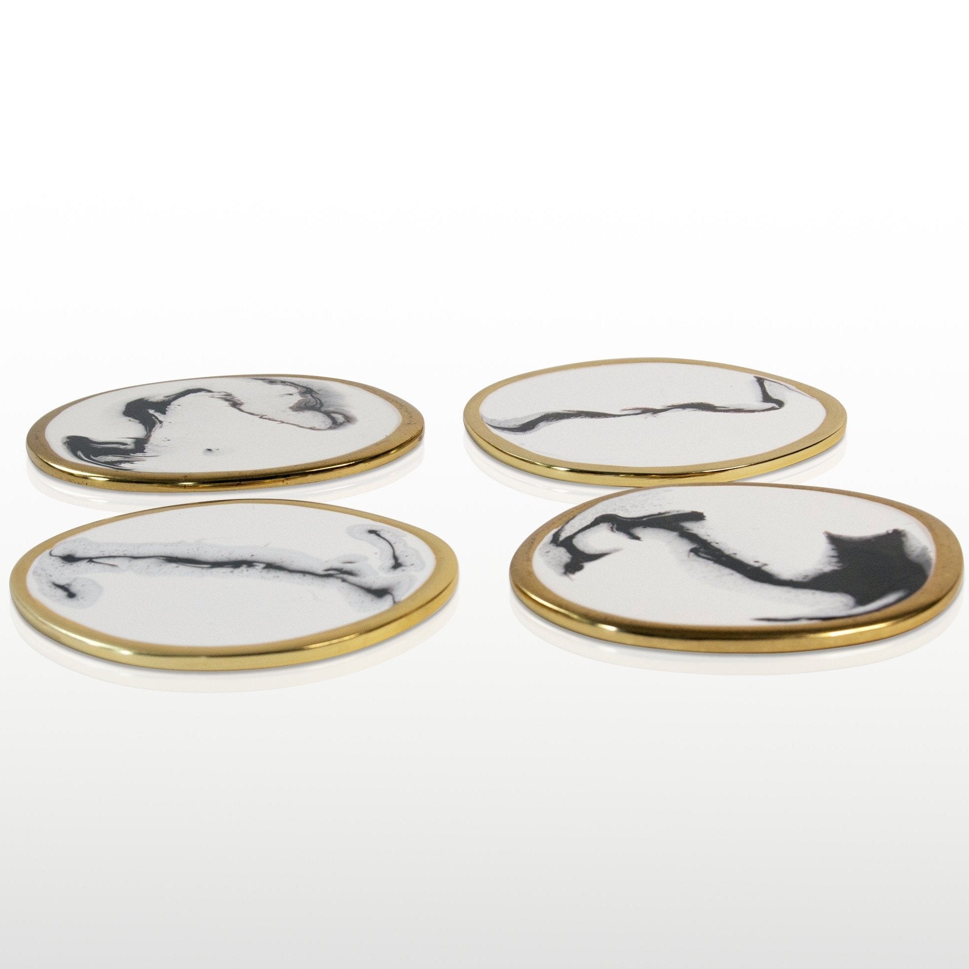 Four coasters with black and white abstract designs on a gold rim against a white background