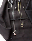 Necklaces shown in a jewelry roll travel case with chevron pattern, unrolled to show compartments for earrings, rings, and necklaces, with jewelry items like earrings, rings, and necklaces organized within it.