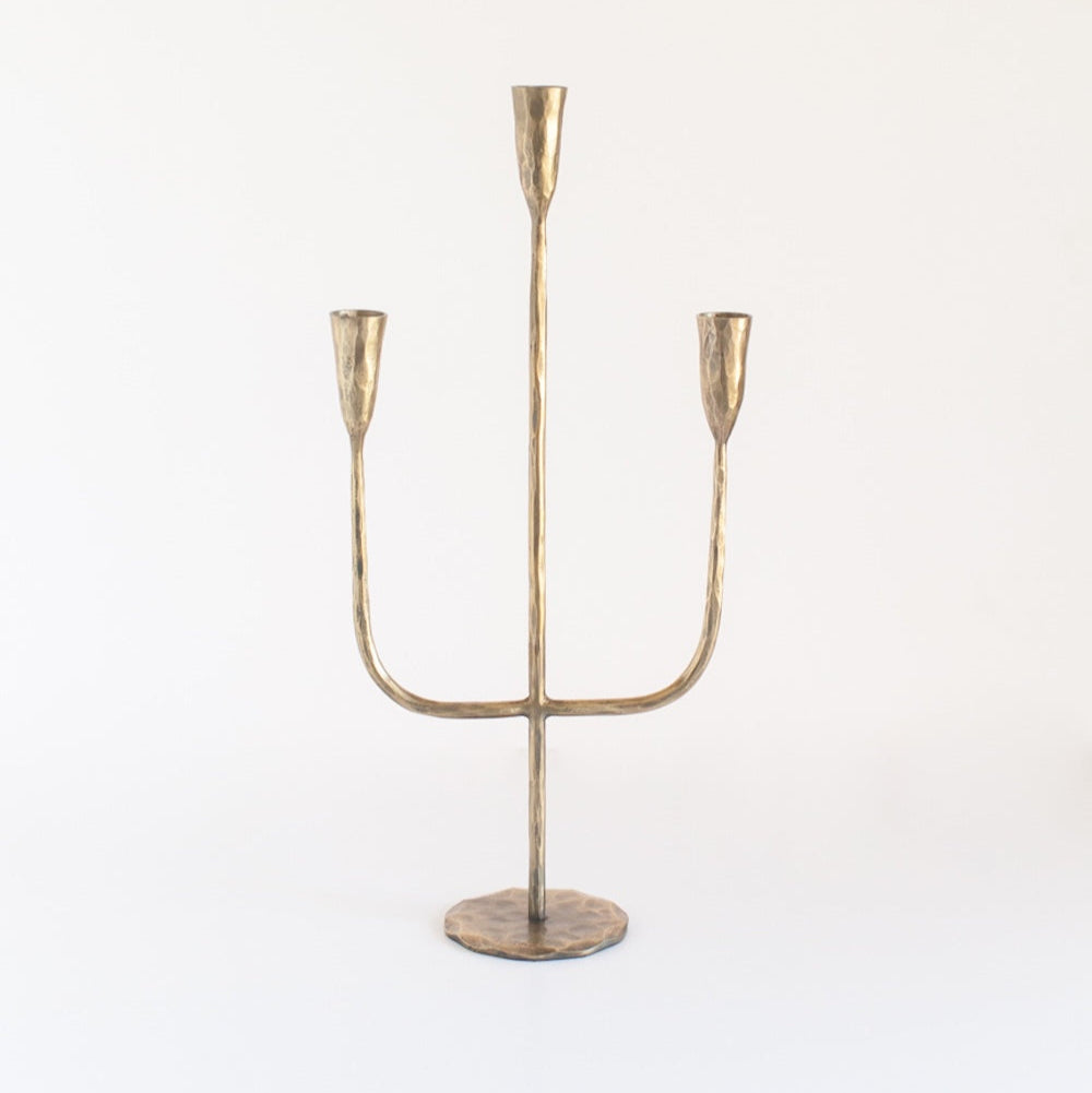 A brass candelabra with a sturdy weighted base and three arms for holding candles.