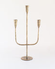 A brass candelabra with a sturdy weighted base and three arms for holding candles.