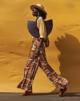 A model carrying a hand-dyed blue, half-moon shaped handbag made from elephant grass, with an open top and two handles.