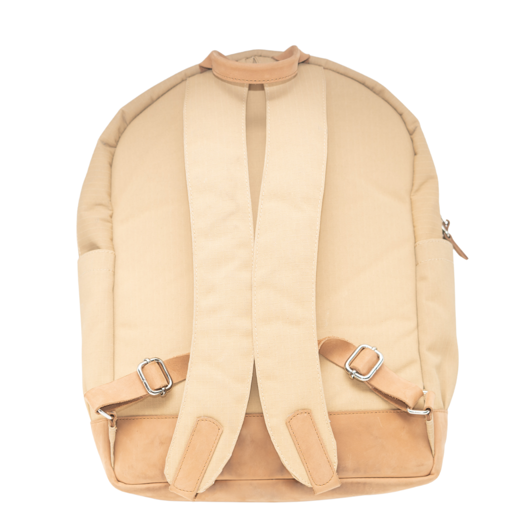 The backside of a beige and brown Cape Buffalo book bag with a large main compartment and a laptop sleeve, made from ripstop canvas with leather accents.