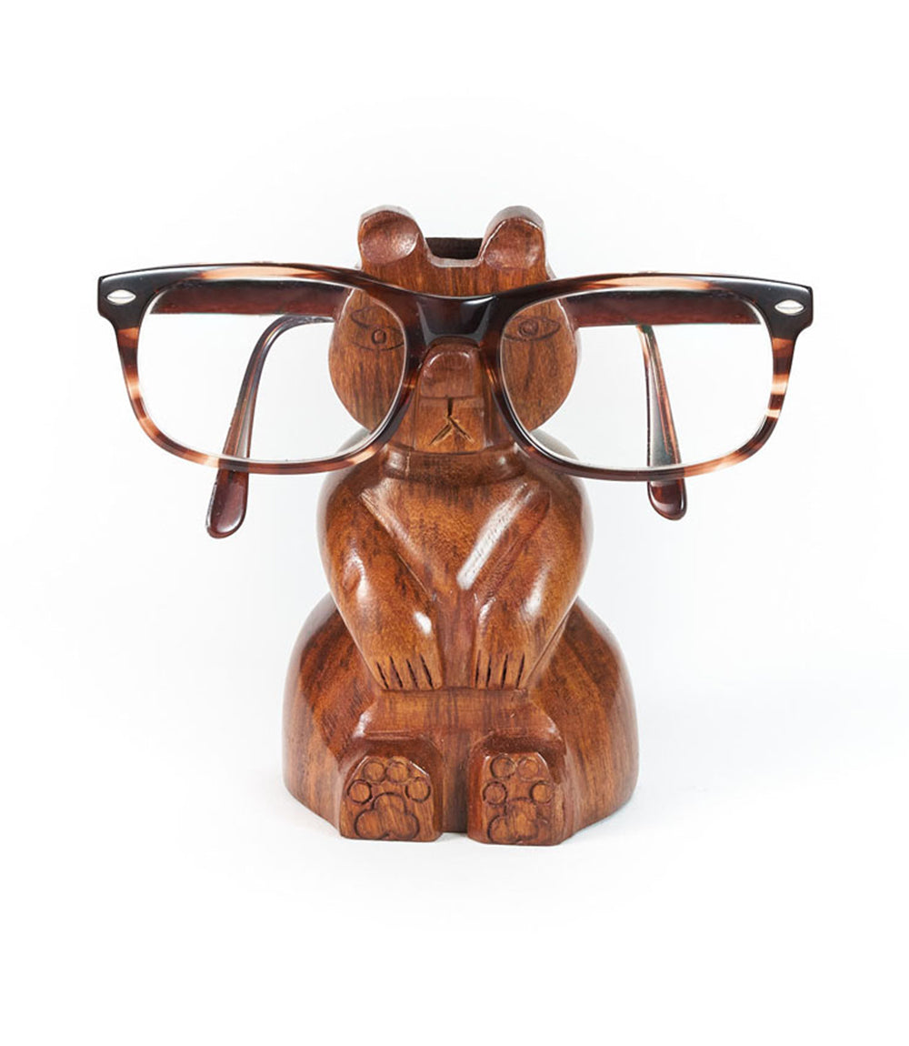 A handcarved wooden bear eyeglasses holder stand with a pair of eyeglasses resting on it