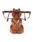 A handcarved wooden bear eyeglasses holder stand with a pair of eyeglasses resting on it