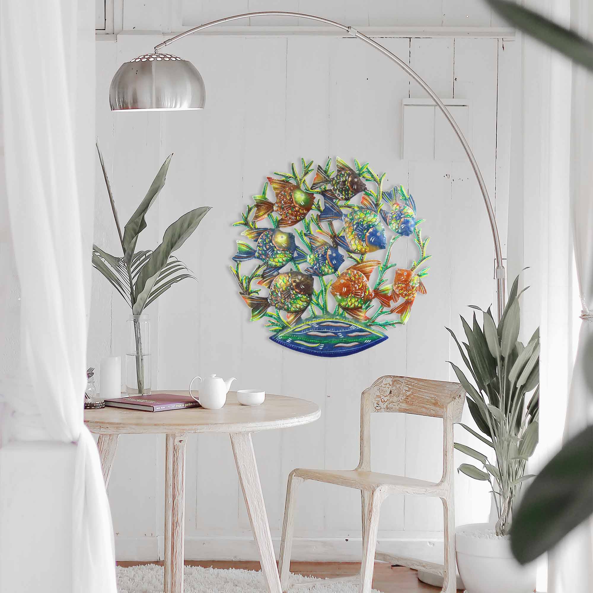 Metal wall art featuring a painted school of fish hanging on a white wall