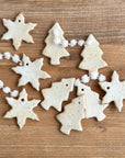 Decorative ceramic ornaments shaped like snowflakes and trees on a wooden surface