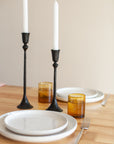 Dining table setting with black candle holders and amber glasses.