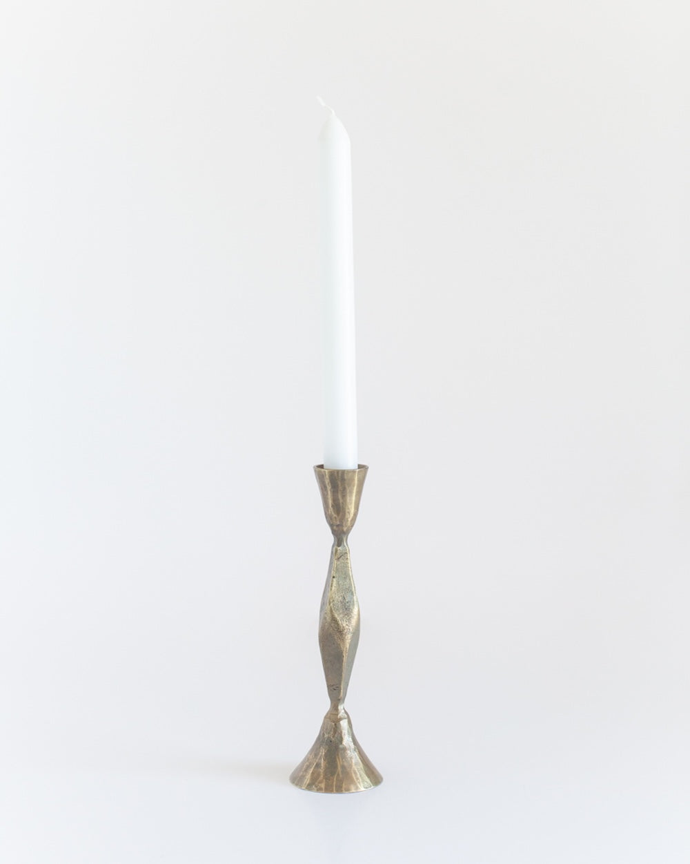 A single brass finish candle holder with a tapered design, standing upright holding a candle against a white background