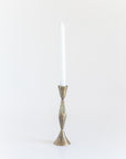 A single brass finish candle holder with a tapered design, standing upright holding a candle against a white background