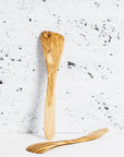 A pair of olive wood spatulas against a textured gray background