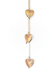 Three gold heart-shaped decorations hanging on a string against a white background