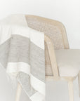 White and gray striped blanket draped over a chair on a white background