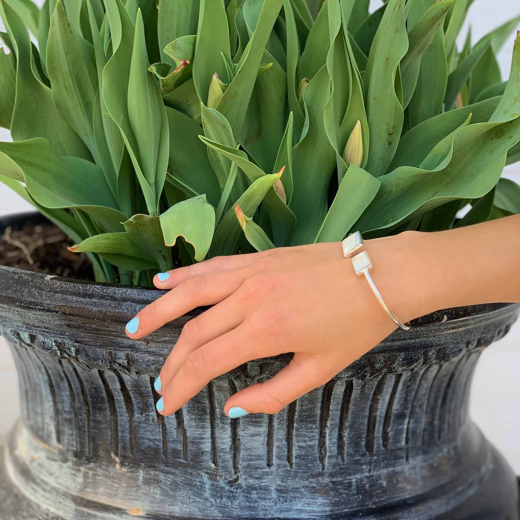 A model wearing a silver-plated cuff bracelet with square caps embedded with Mother of Pearl, displayed against a white background.